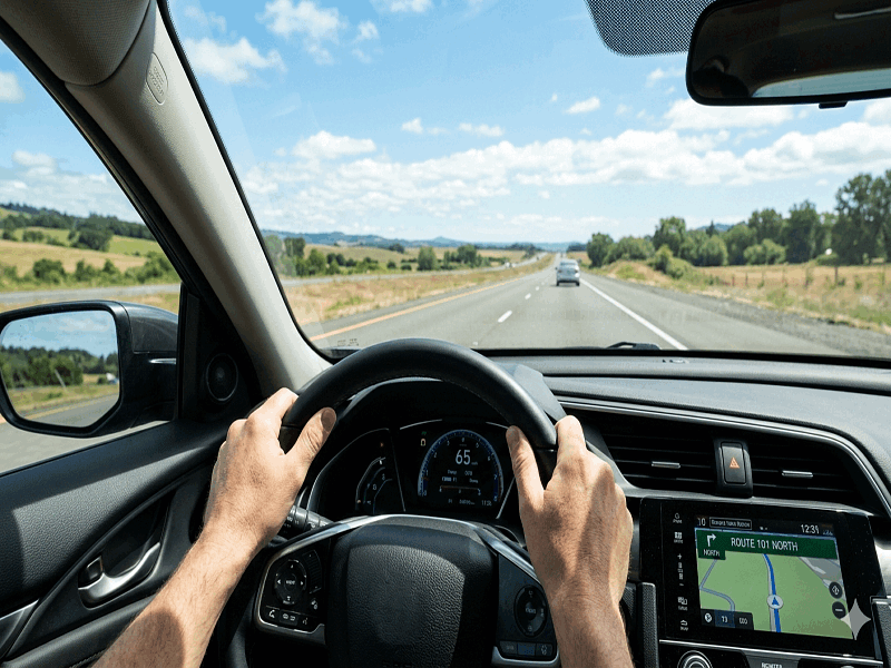 Driving Close up view of a person safely steering a vehicle down an open road.